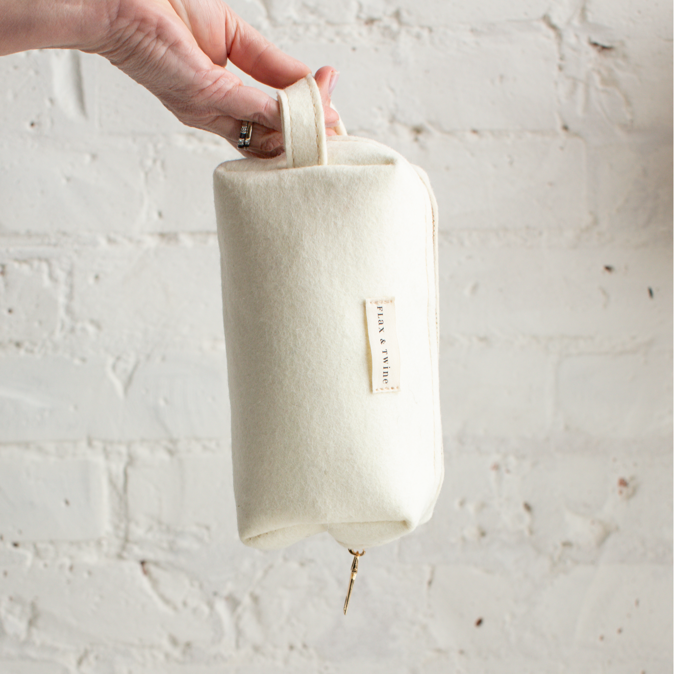 Off white notions or project bag held by a hand with a white background