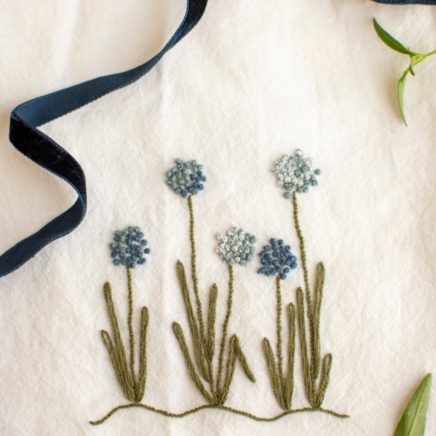 Embroidered floral design on a white fabric with a blue ribbon.
