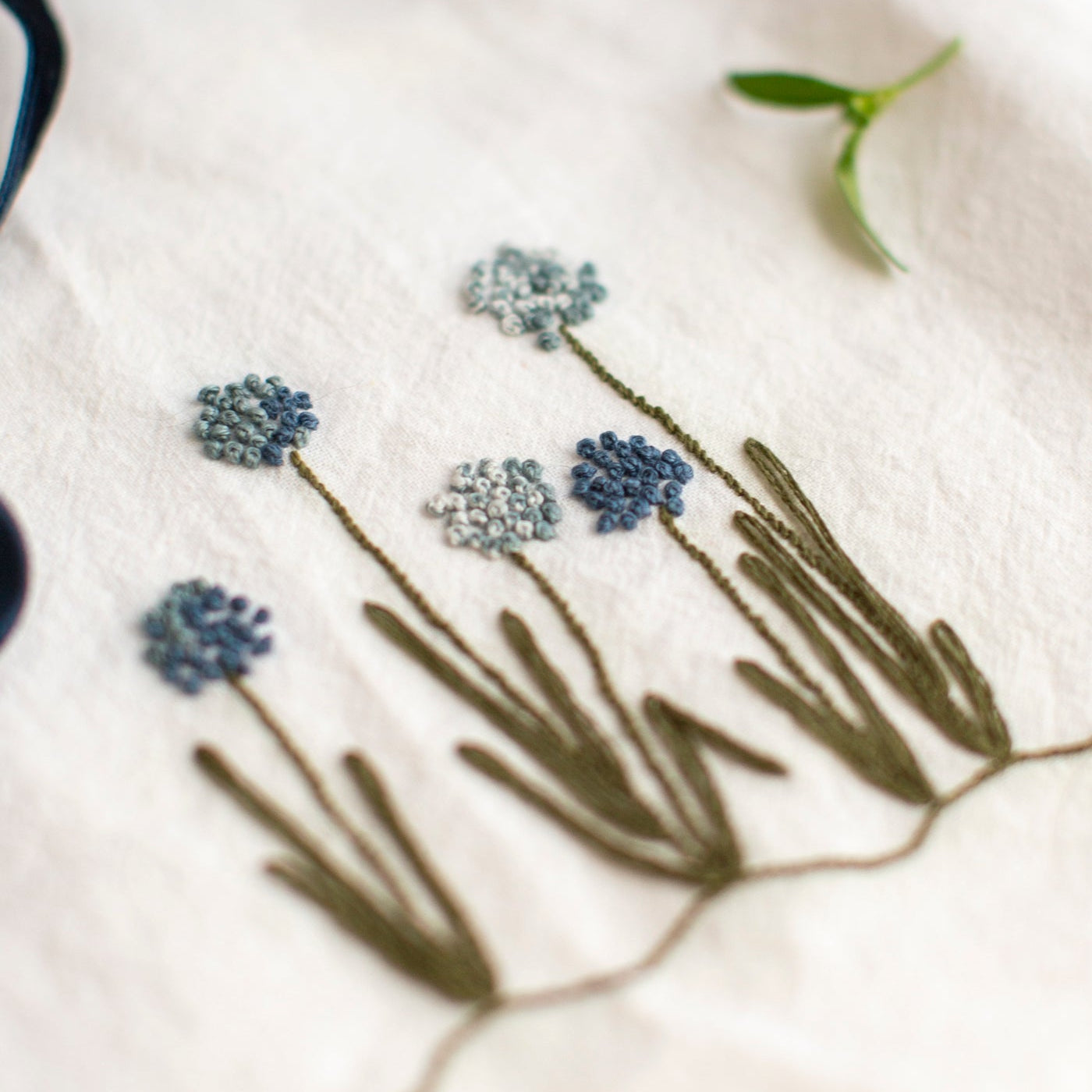 Embroidered flowers on a white fabric with a blue ribbon